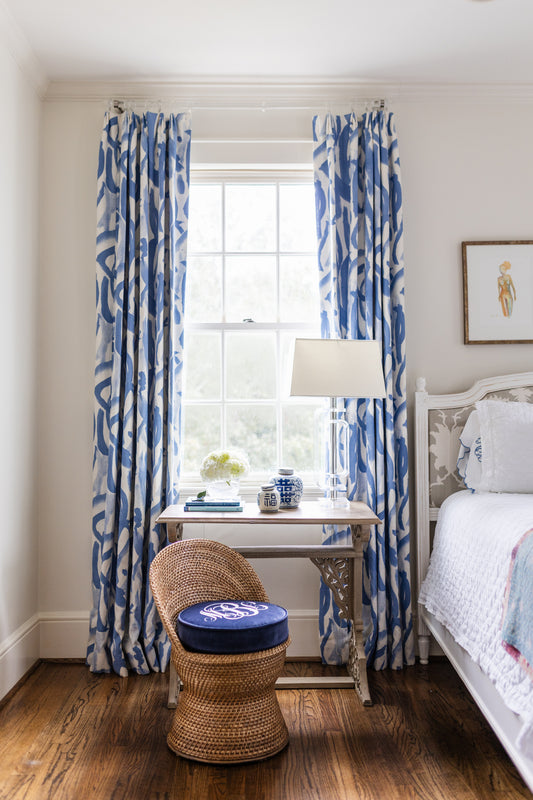 Wicker stool in front of a side table with monogrammed cushion